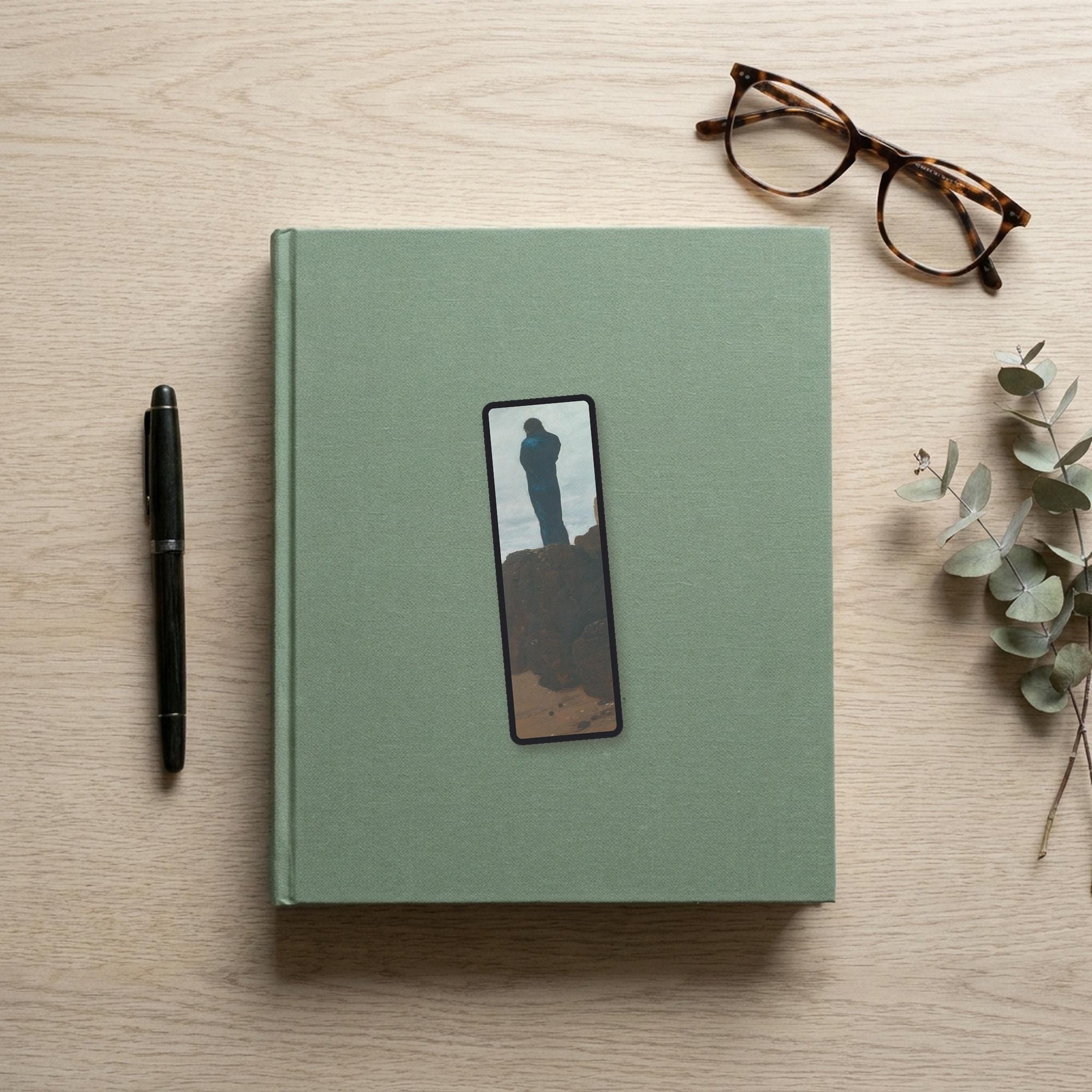 The Wanderer Odyssey bookmark flat lay on a desk with a book, pen and reading glasses