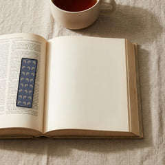 The Wine-Dark Sea Odyssey bookmark lying on an open book, the page text visible through the sheer organza