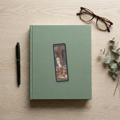 Bound to the Mast Odyssey bookmark flat lay on a desk with a book, pen and reading glasses