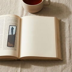 The Wanderer Odyssey bookmark lying on an open book, the page text visible through the sheer organza
