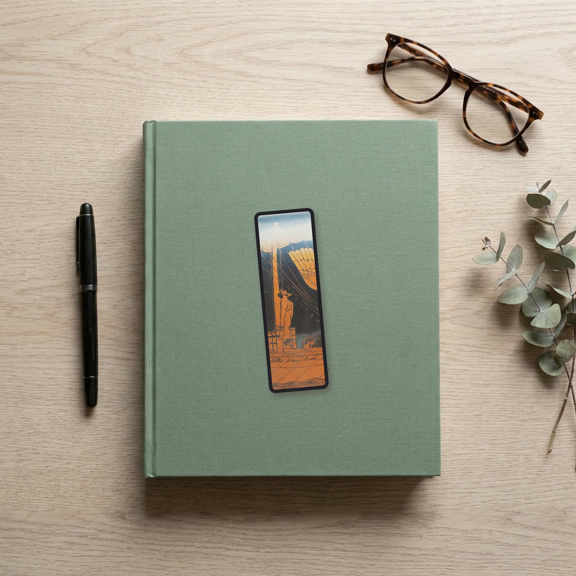 The Siren Vase Odyssey bookmark flat lay on a desk with a book, pen and reading glasses