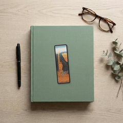 The Siren Vase Odyssey bookmark flat lay on a desk with a book, pen and reading glasses