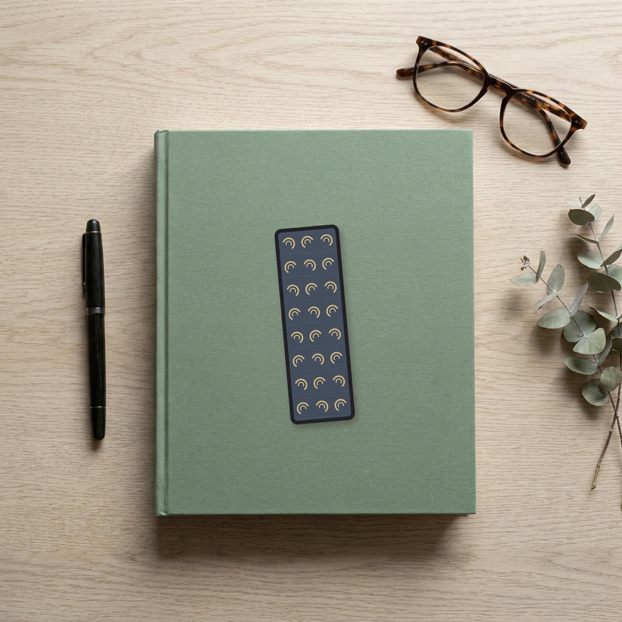 The Wine-Dark Sea Odyssey bookmark flat lay on a desk with a book, pen and reading glasses