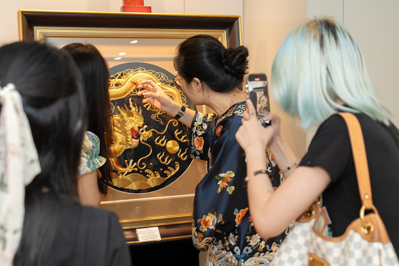 Joni Zhou demonstrating imperial goldwork embroidery to workshop guests